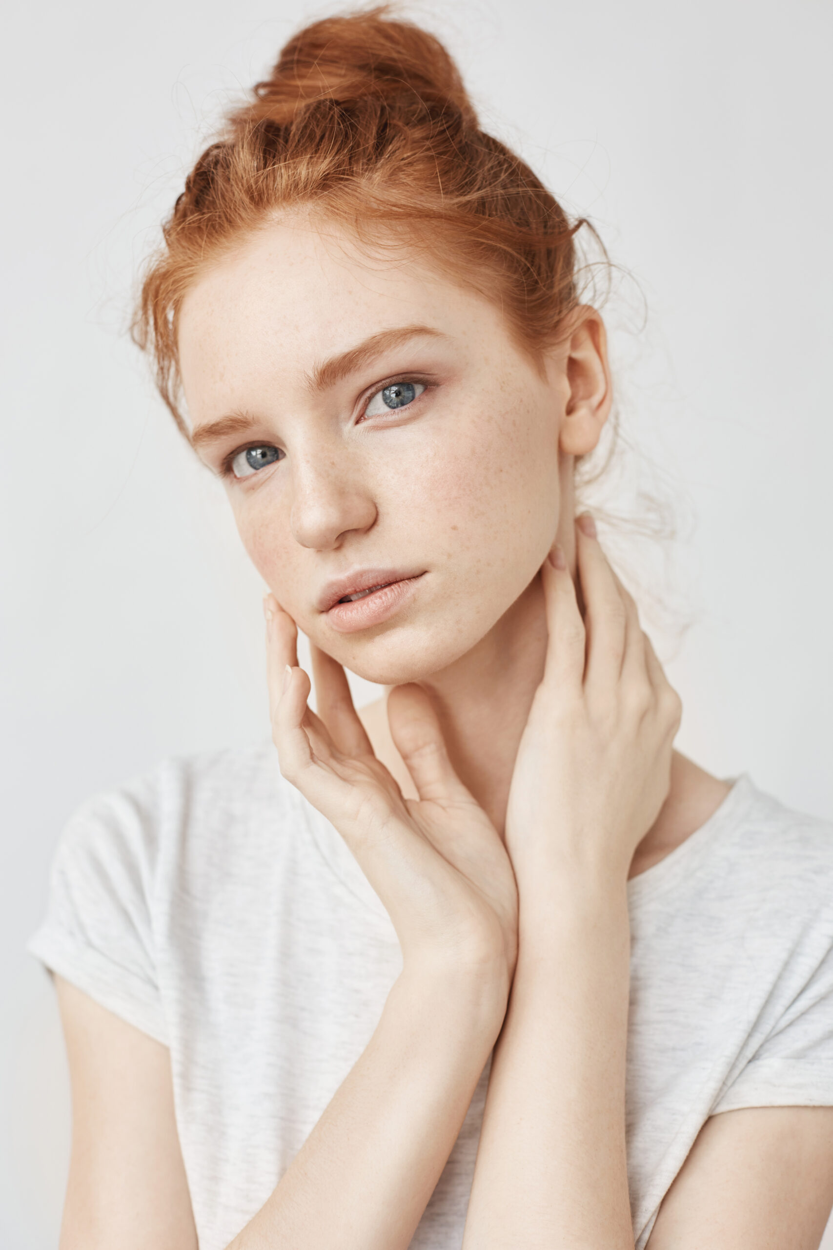 Portrait of young bbeautiful natural redhead model looking at camera over white background.