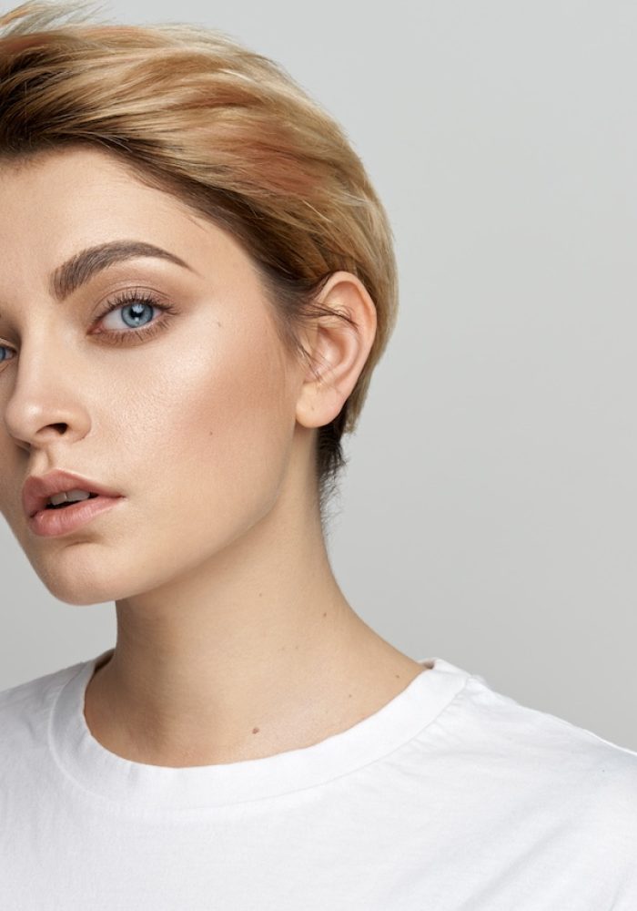 Portrait of young female model with short hair isolated on gray background