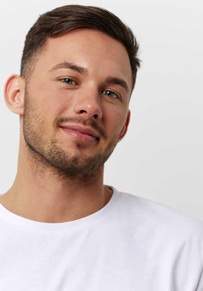 Cheerful cute happy young tanned handsome man in basic t-shirt smile at camera posing isolated on over white studio background. Copy space Banner Mockup. People emotions Lifestyle concept. Portrait