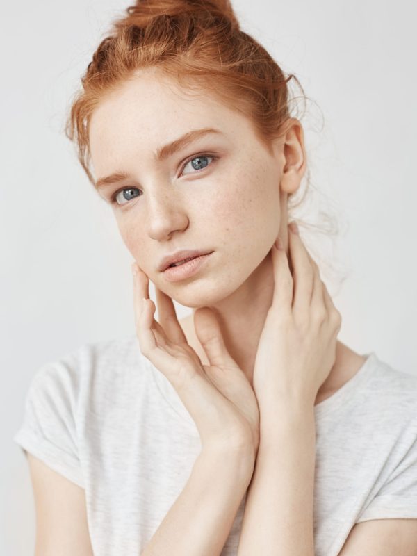 Portrait of young bbeautiful natural redhead model looking at camera over white background.